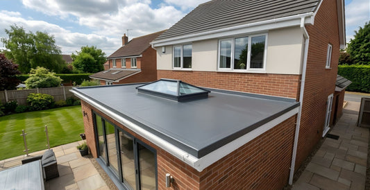 A professional GRP fibreglass flat roof installation on a modern brick home extension, featuring a seamless dark grey finish, integrated roof lantern skylight, and clean white perimeter trims.