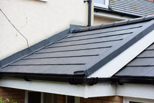 Fibreglass flat roof with simulated lead flashings and traditional dark trims on a UK garage, giving a classic lead roof appearance