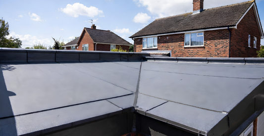  Seamless grey GRP fibreglass flat roof on a British suburban garage extension with neat edge trims under clear sky