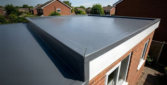 A sleek grey GRP flat roof on a UK brick extension, showing a visible stress crack forming at the edge trim corner due to thermal expansion.