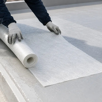 Worker laying 225g chopped strand mat on flat roof for GRP roofing resin reinforcement