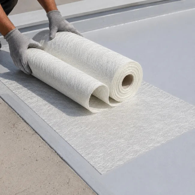 Worker laying fibreglass chopped strand matting on flat roof during GRP roofing installation