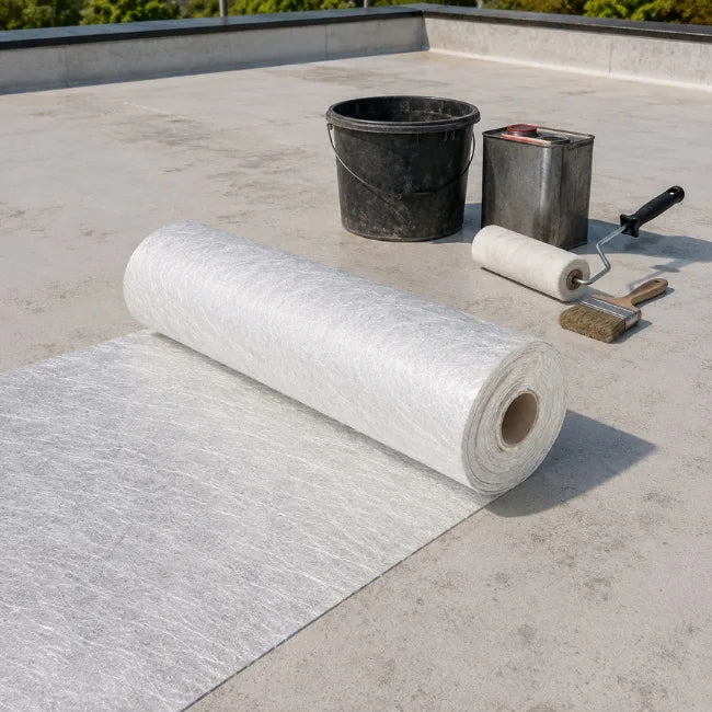 Chopped strand fibreglass matting roll on flat roof with resin tools for GRP roofing work