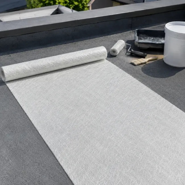 225g fibreglass chopped strand mat rolled out on flat roof with GRP roofing tools and resin